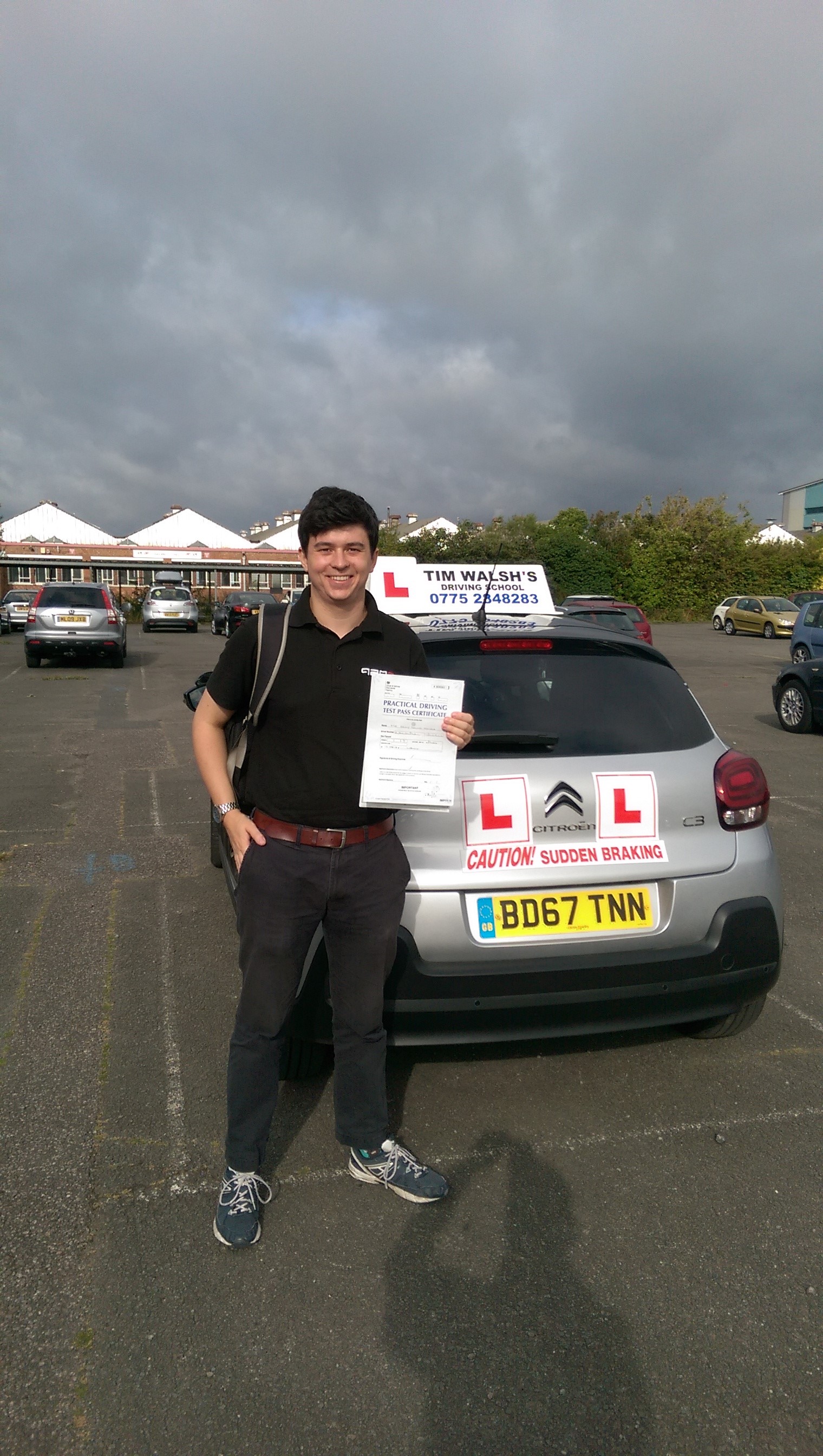 Past student Huq holding his test certificate next to the instructor car