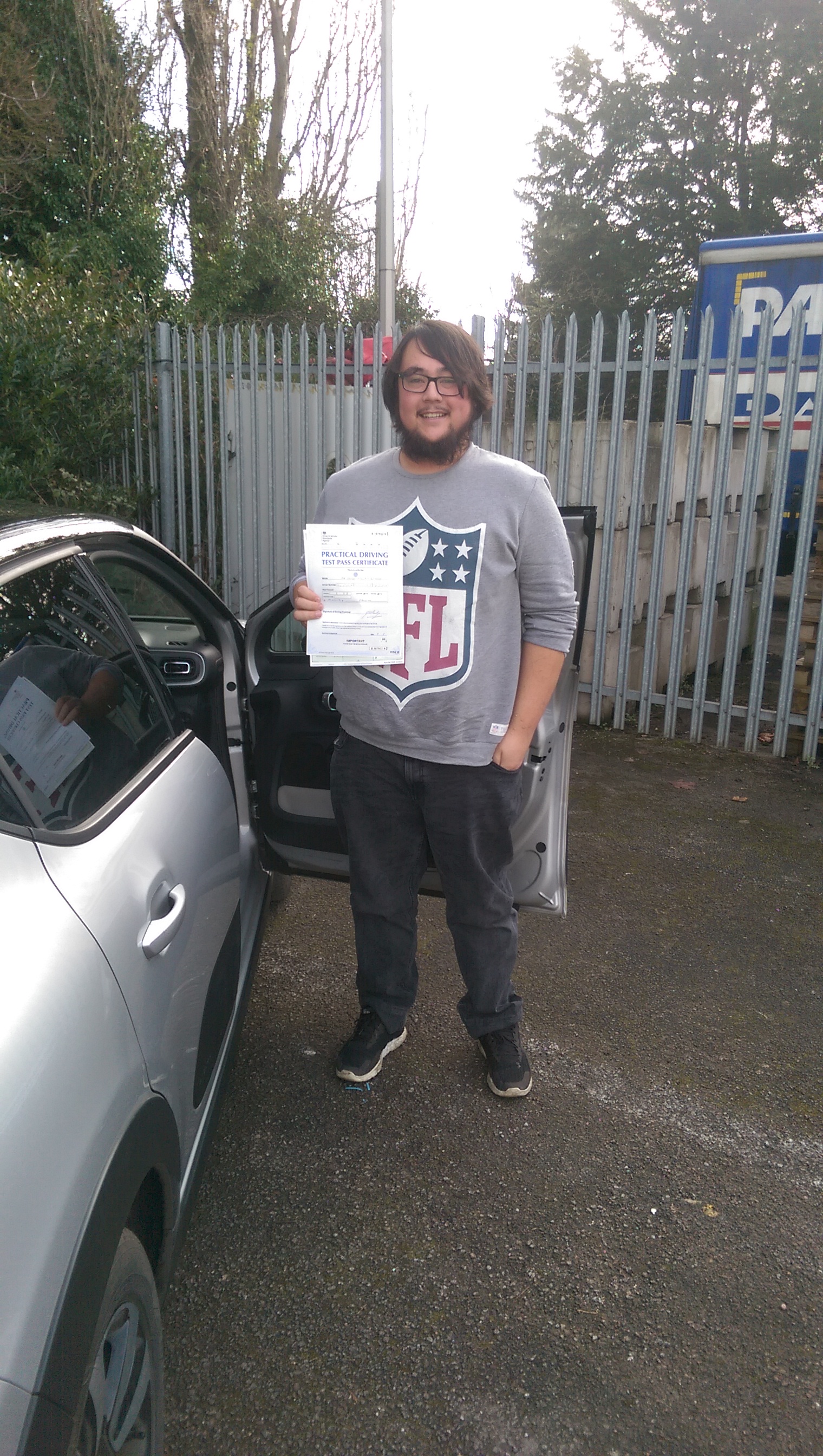 Past student James holding his test certificate next to the instructor car